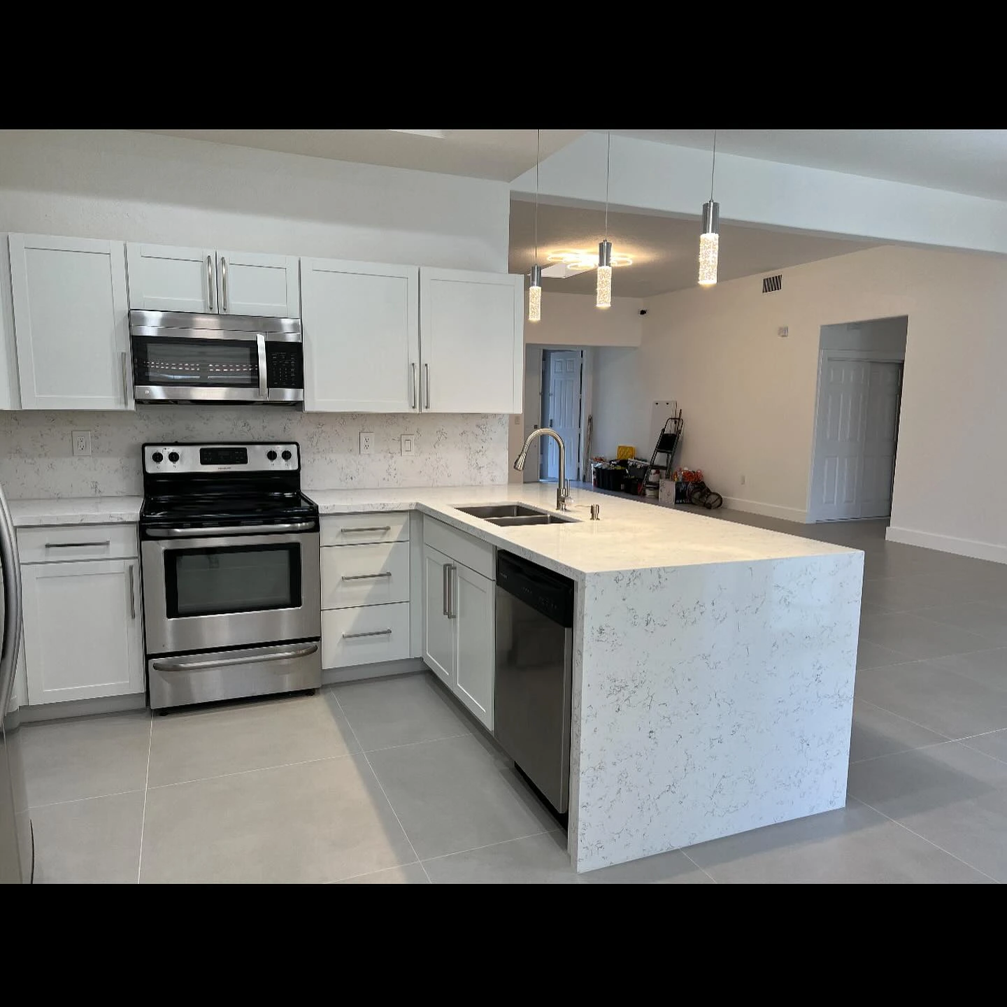 After: renovated kitchen with white cabinetry, a waterfall counter, and a finished tile floor
