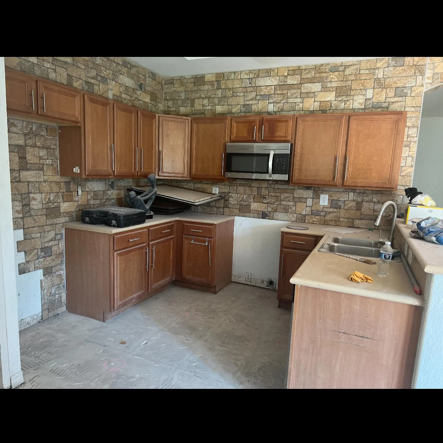 Before, wider angle: original wood cabinets, stone walls, and open appliance space